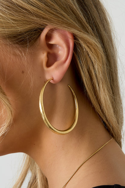 Silver thick oval Elena hoop earrings worn in the ear from Sorea Fashion.