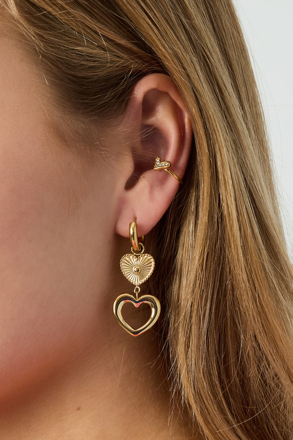 Gold Emi heart-shaped stud earrings worn in the ear from Sorea Fashion.