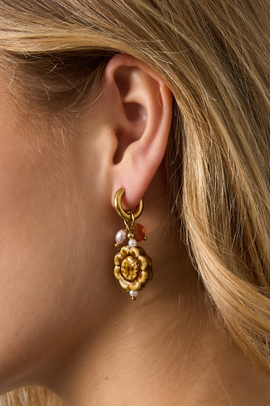 Gold floral-shaped Flora earrings worn in the ear with a polished finish from Sorea Fashion.