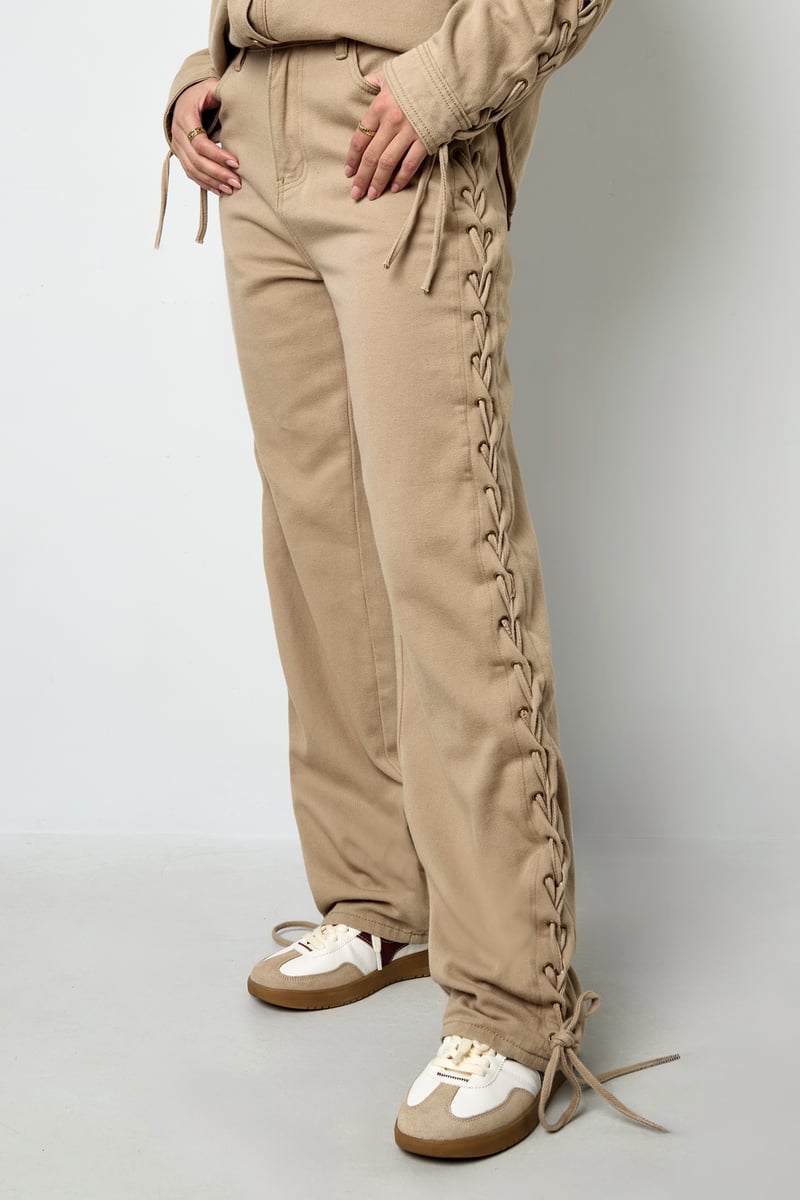 Model posing in neutral Olea Jeans Sorea Fashion trousers with a coordinating top.