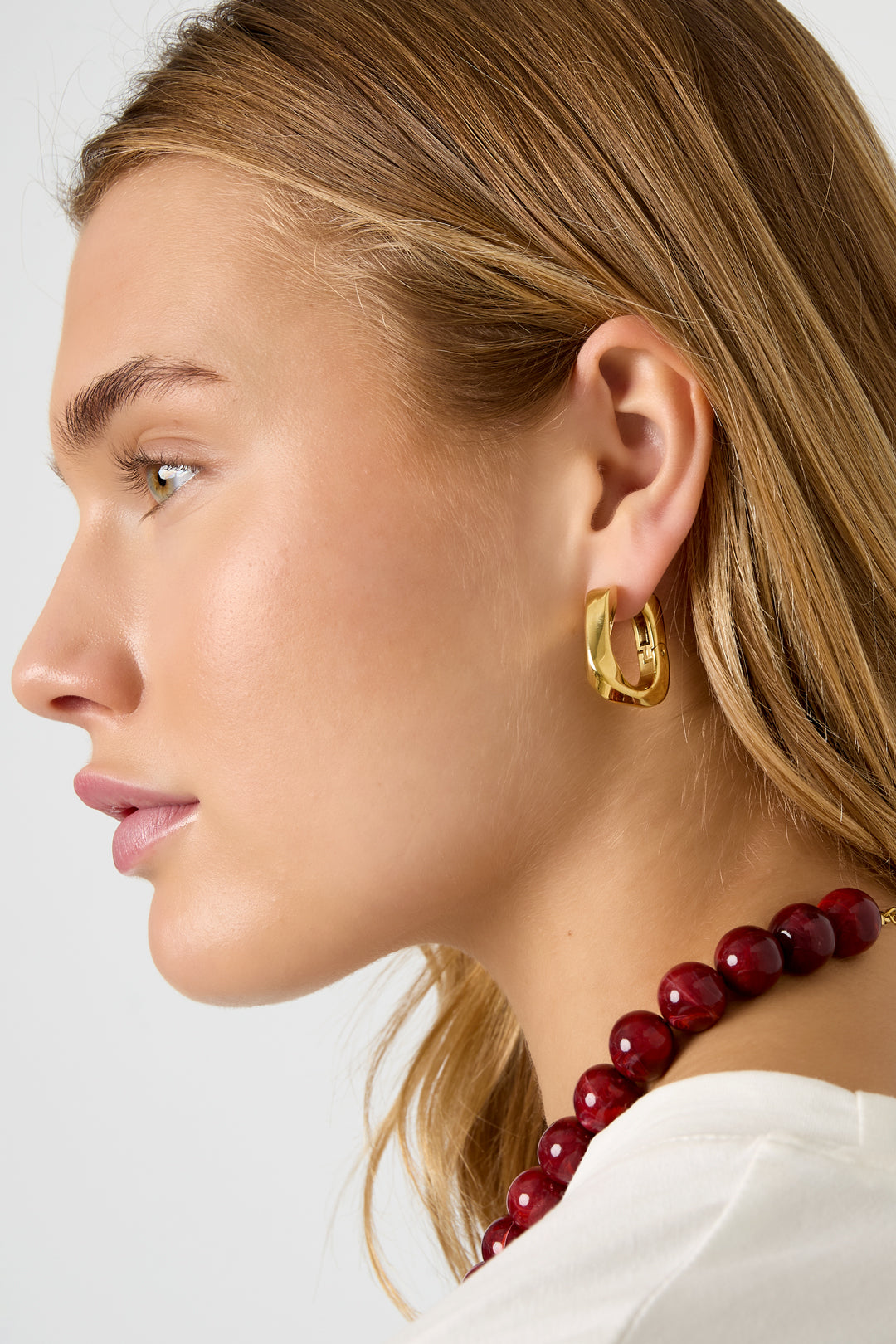 Gold Rhea earrings featuring a thick squared hoop design worn in the ear from Sorea Fashion.