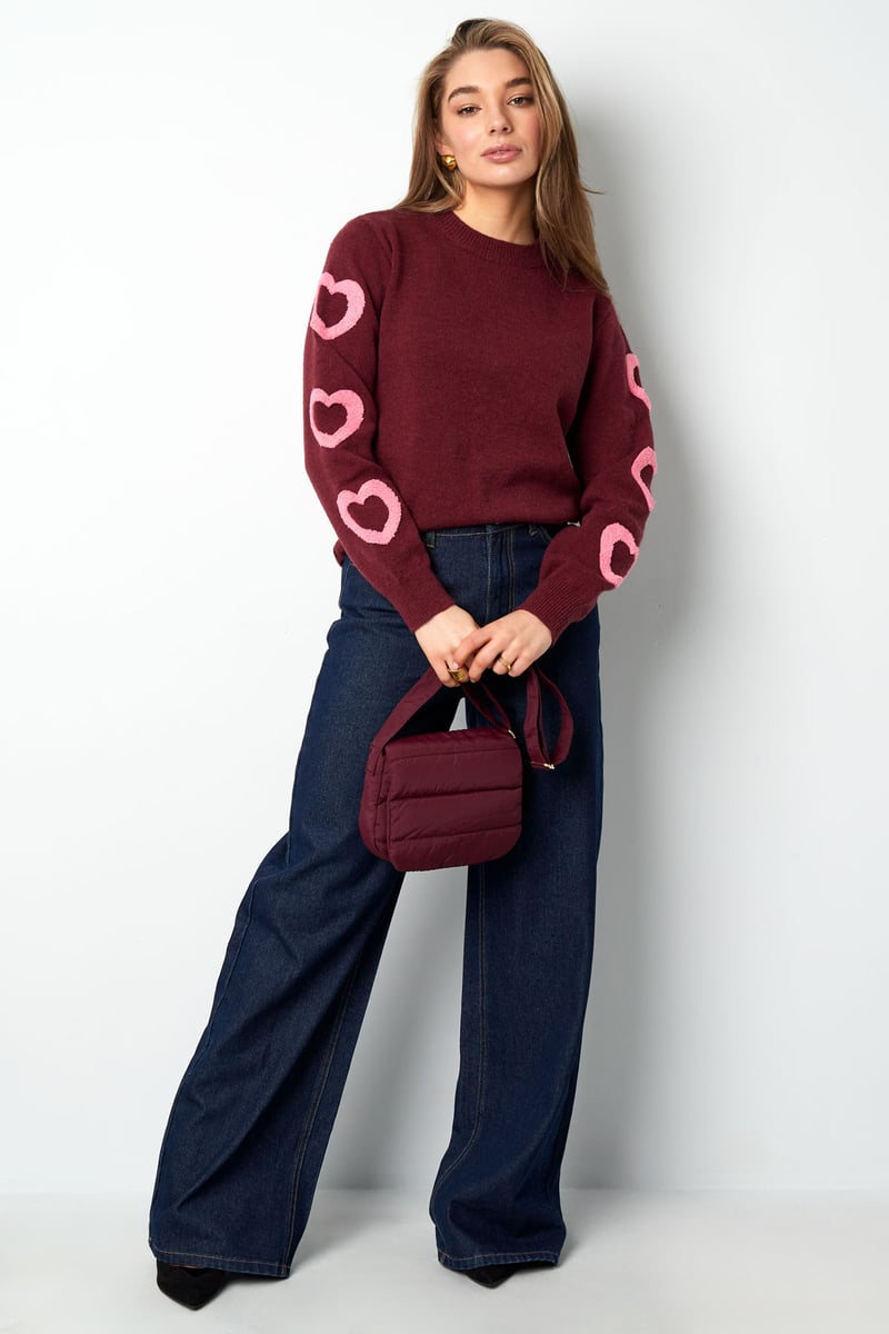 Model posing in the relaxed Urie Sweater Sorea Fashion paired with trousers.